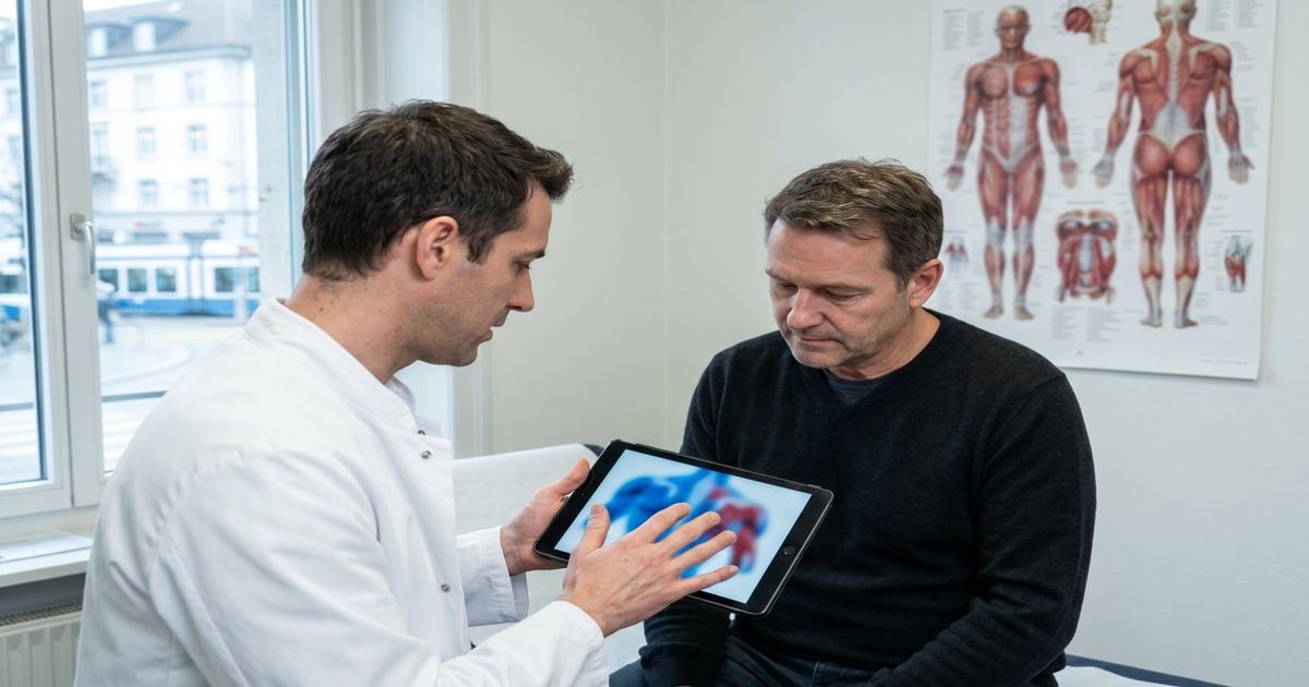 Ärztin in einer Schweizer Praxis erklärt einem Patienten sachlich die mögliche Wirkung von medizinischem Cannabis auf Muskelspastik und Muskelentspannung anhand eines Schaubilds