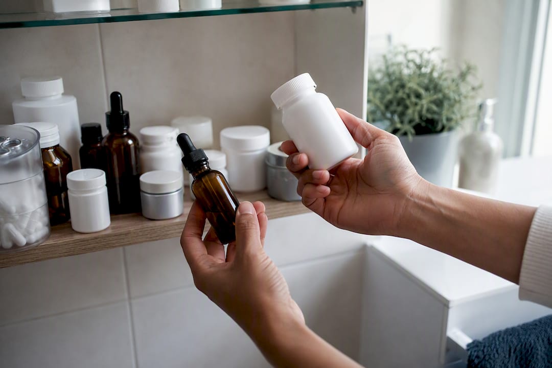 Hände, die verschiedene rezeptfreie Medikamente und Nahrungsergänzungsmittel halten